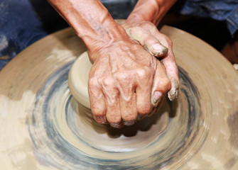 Close-up of hands making pottery on pottery wheel