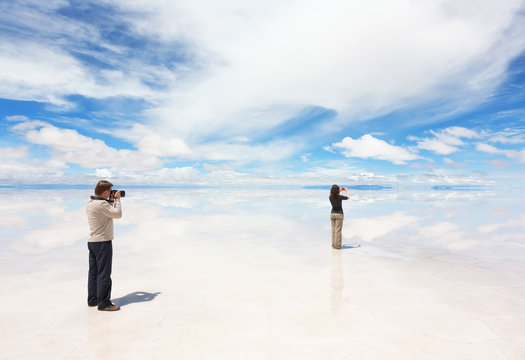 Man and woman take photo of panorama lake Salar de Uyuni