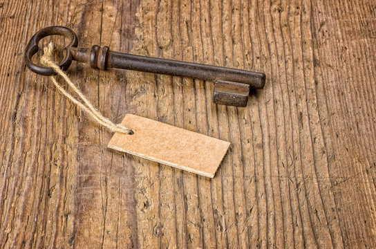 Alter Schlüssel mit Anhänger auf einem Holzbrett