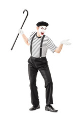 Full length portrait of a mime artist holding a cane and gesturi