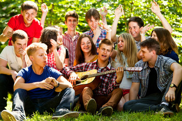 Happy school friends singing by guitar