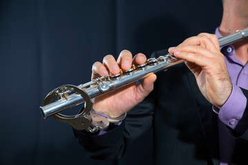 professional flutist musician playing flute on black background