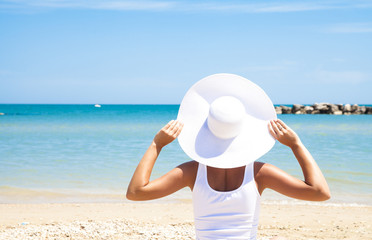 Ragazza con cappello bianco con sfondo di mare rilassandosi