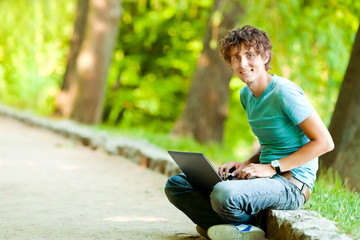 Naklejka na ściany i meble Happy man with a laptop in outdoor