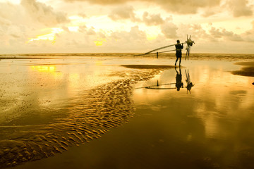 Fishermen at dawn sky background with sun rays and reflected in