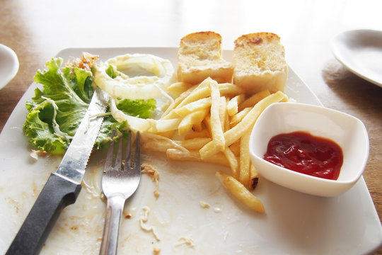 Left Over Food On Plate With Fork And Knife