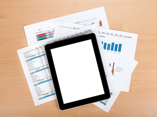 Tablet with blank screen over papers with numbers and charts