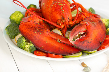 Red lobster on platter with vegetables on wooden table close-up