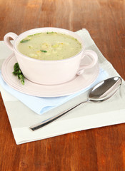 Nourishing soup in pink pan on wooden table close-up