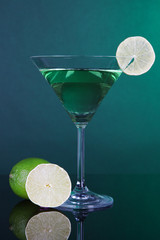 Green cocktail with lime on dark green background