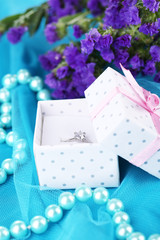 Flowers  and engagement ring on blue cloth