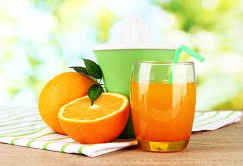 Citrus press, glass of juice and ripe oranges
