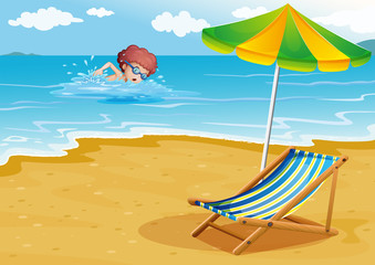 A boy swimming at the beach with a chair and an umbrella