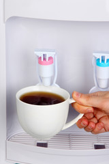 Woman filling cup at water cooler
