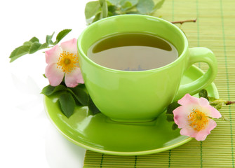 Cup of herbal tea with hip rose flowers, isolated on white