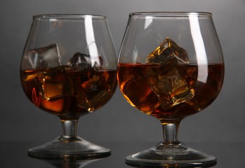 Brandy glasses with ice on grey background