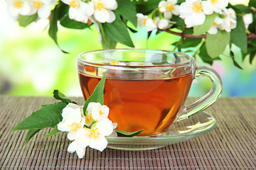 Cup of tea with jasmine, on bamboo mat, on bright background
