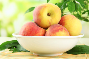 Ripe sweet peaches on table in bowl, outdoors