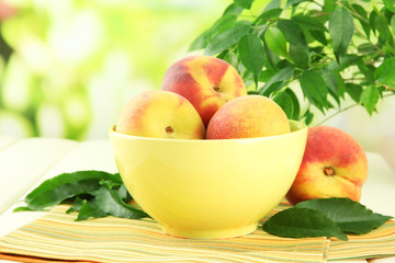 Ripe sweet peaches on table in bowl, outdoors