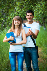 Two students studying in park with book outdoors