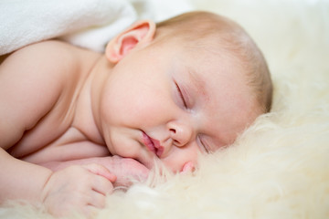 newborn baby girl sleeping on fur bed