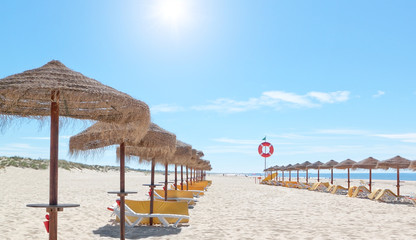 Beautiful sunny beach in Portugal with beach umbrellas and sun b