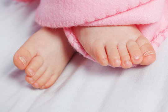 Cute fingers on the legs of the infant. In a pink blanket.