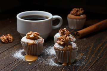 Cupcake with nuts and caramel on old wooden table