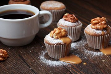 Cupcake with nuts and caramel on old wooden table