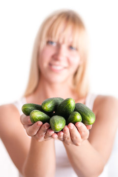 Woman holding bunch of cucumbers on hands