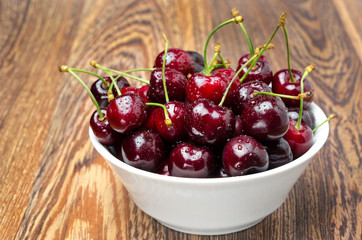 bowl of fresh cherries on a wooden background, close-up