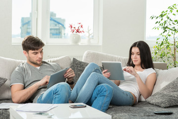 couple sitting on a couch with tablet computers