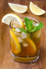 glass of ice tea with lemon and mint on a wooden background