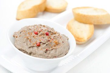 liver pate with pink pepper in a white bowl and toasted bread