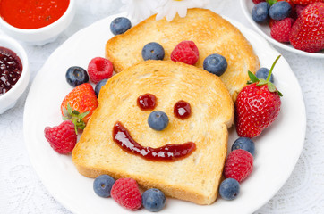 Toast with a smile out of a jam, fresh berries and two jam