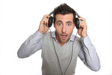 Portrait of astonished guy taking headphones off
