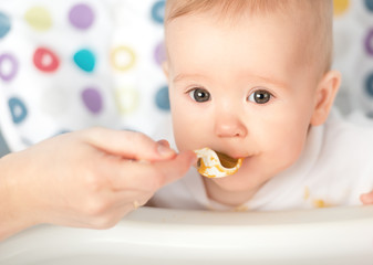 Mother feeds funny baby from  spoon