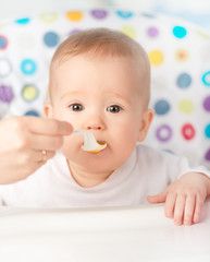 Mother feeds funny baby from  spoon