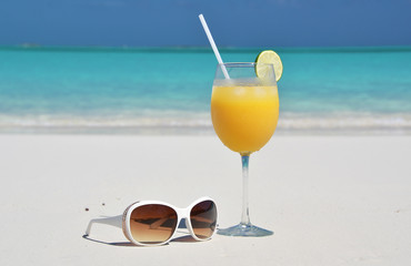 Orange juice and sunglasses on the beach. Exuma, Bahamas