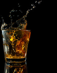 Glass of whiskey with splash, isolated on black