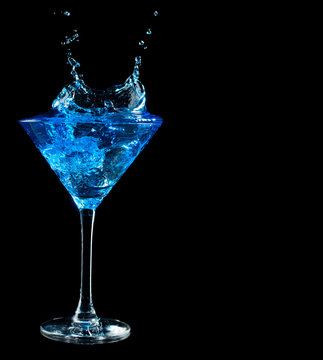 blue cocktail splashing into glass on black