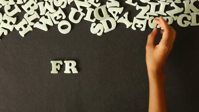 A person spelling Friday with Plastic letters