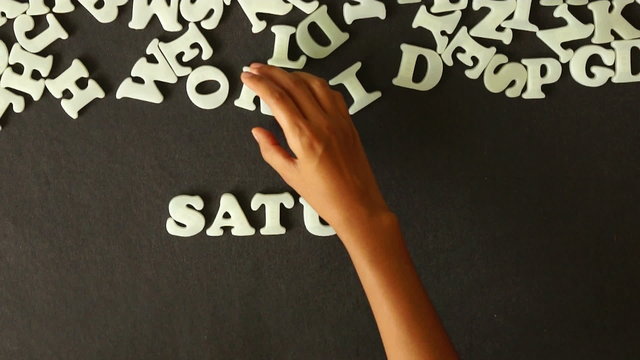 A person spelling Saturday with Plastic letters