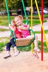 Beautiful little girl on a swings outdoor in the playground