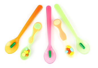 Plastic spoons with color pills, isolated on white