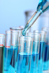 Laboratory pipette with drop of color liquid over glass test