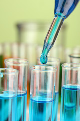 Laboratory pipette with drop of color liquid over glass test