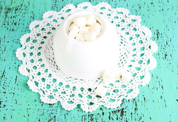 Refined sugar in white sugar bowl on wooden background