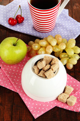 Unrefined sugar in white sugar bowl on wooden background