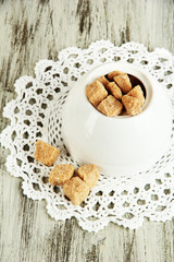 Unrefined sugar in white sugar bowl on wooden background